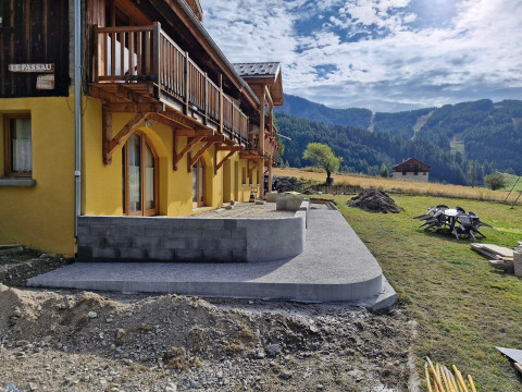 Automne 2024 : Une terrasse en Lauzes avec une rampe d'accès "au sec" devant les appartements du RdC (travaux en cours)